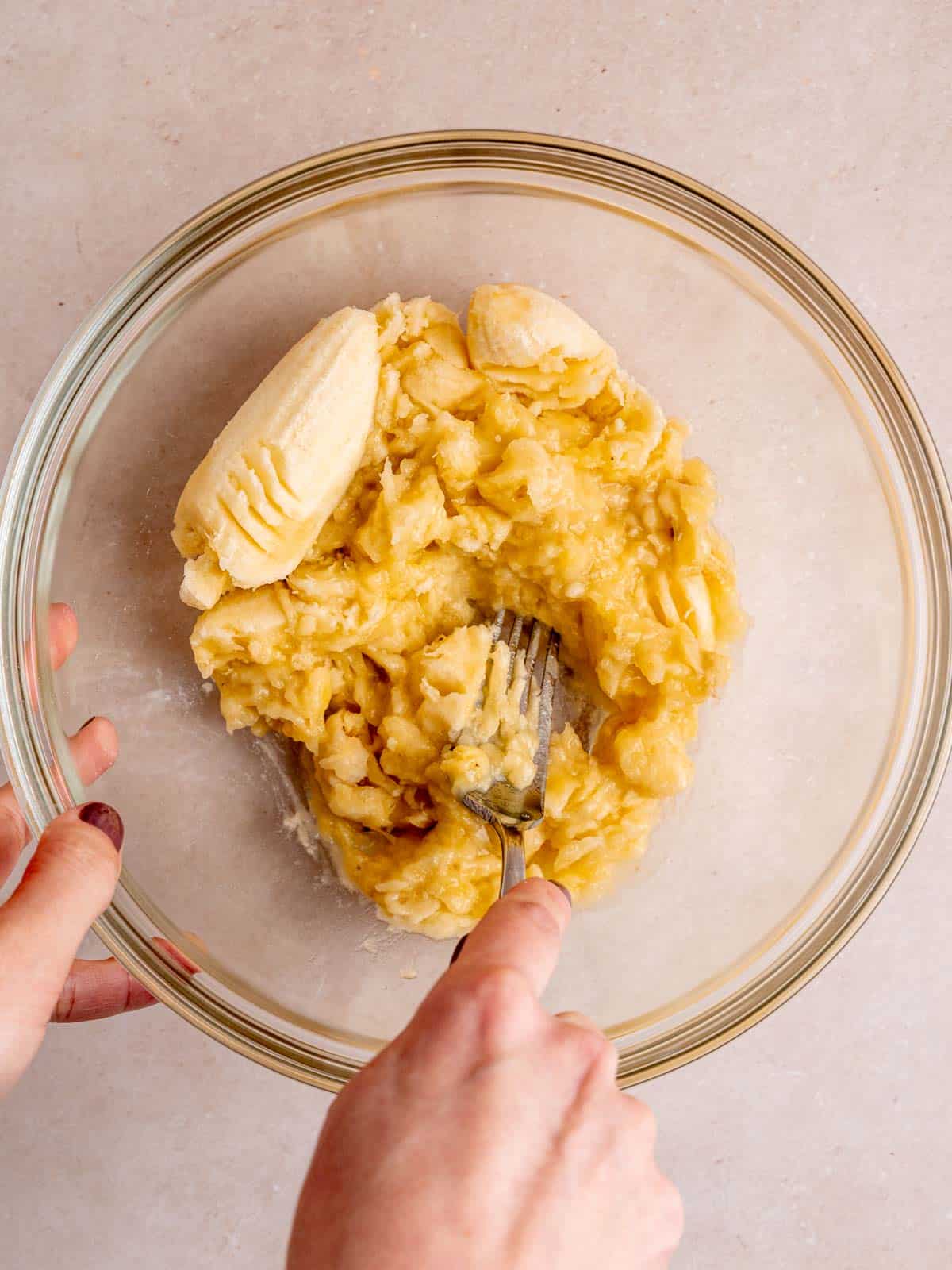 Mashing overripe bananas in a bowl with a fork.
