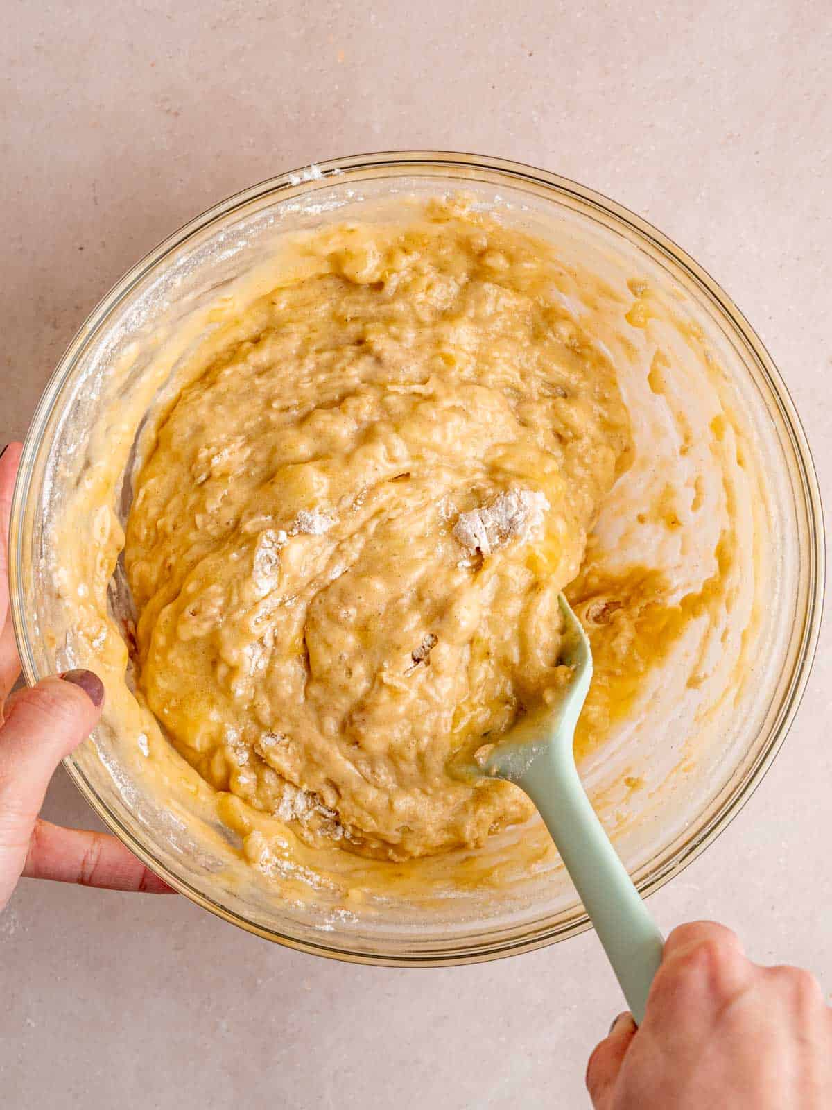 Folding flour, baking soda, cinnamon, and salt into a bowl of wet banana bread ingredients.