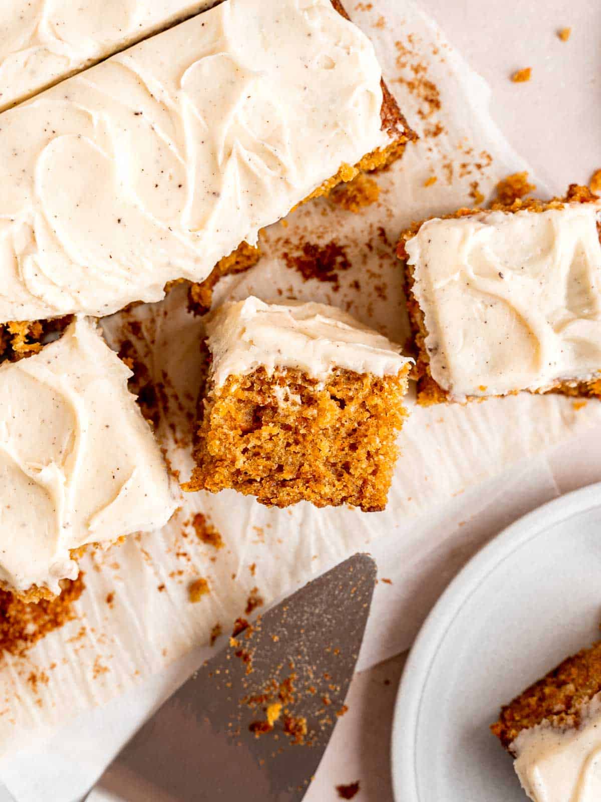 Top view of a carrot sheet cake with brown butter frosting cut into squares.