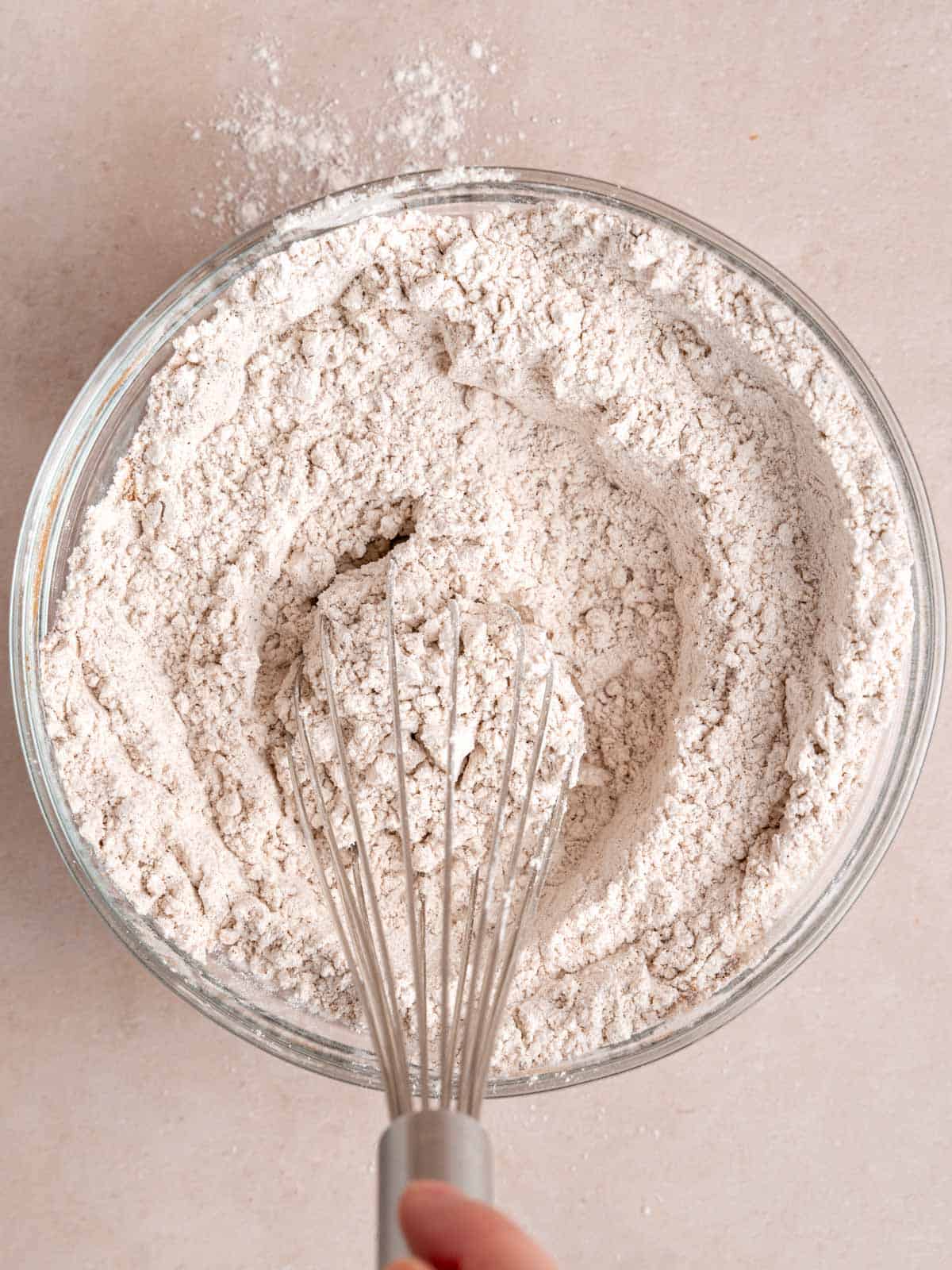 Whisking together dry ingredients for spiced carrot cake in a bowl.