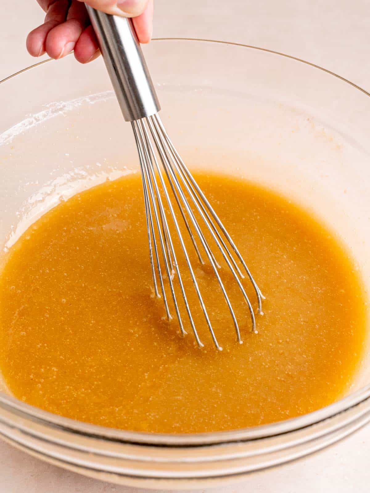 Whisking wet carrot cake ingredients in a bowl.