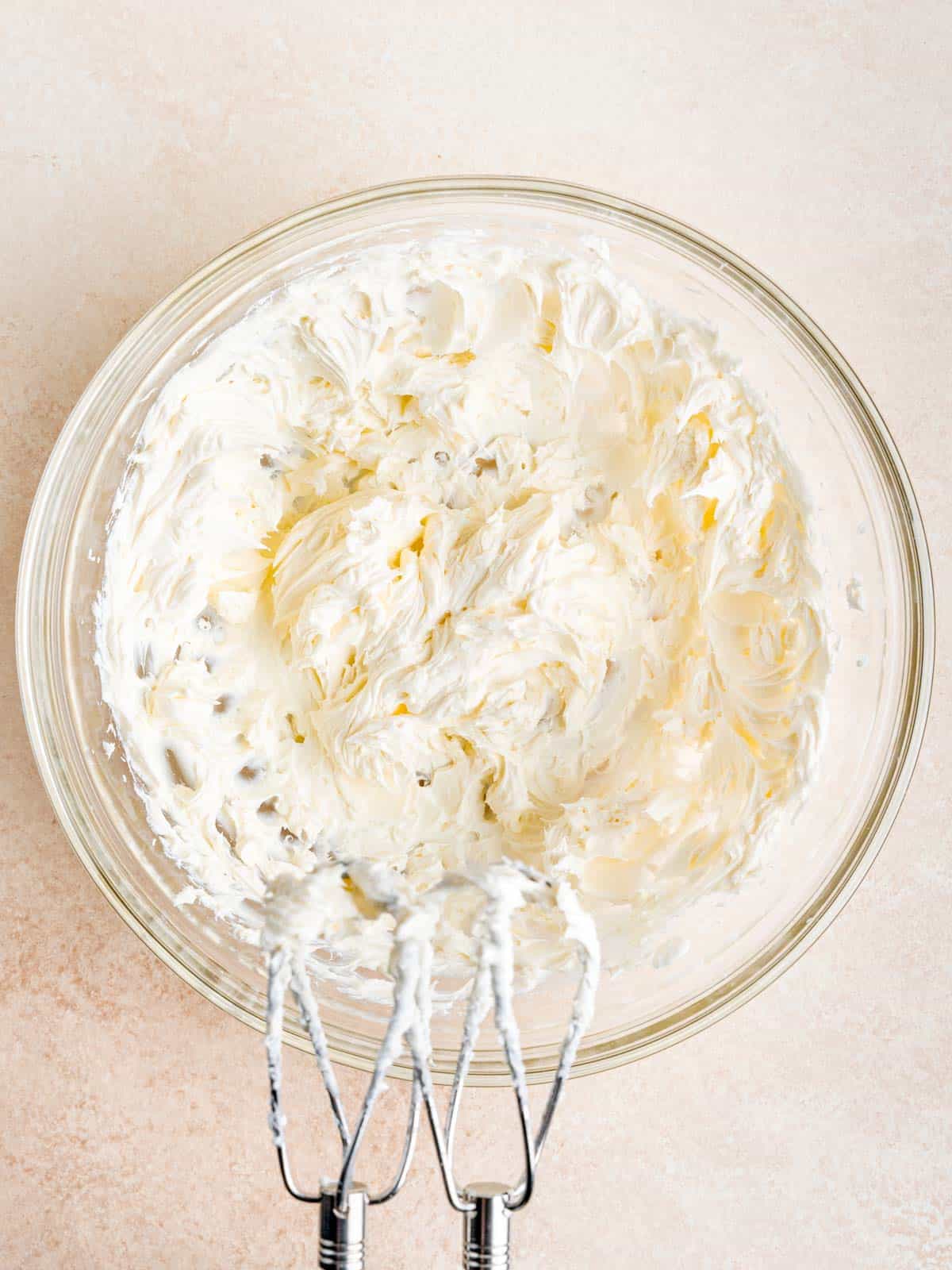 Cream cheese mixture in a bowl with a hand mixer.