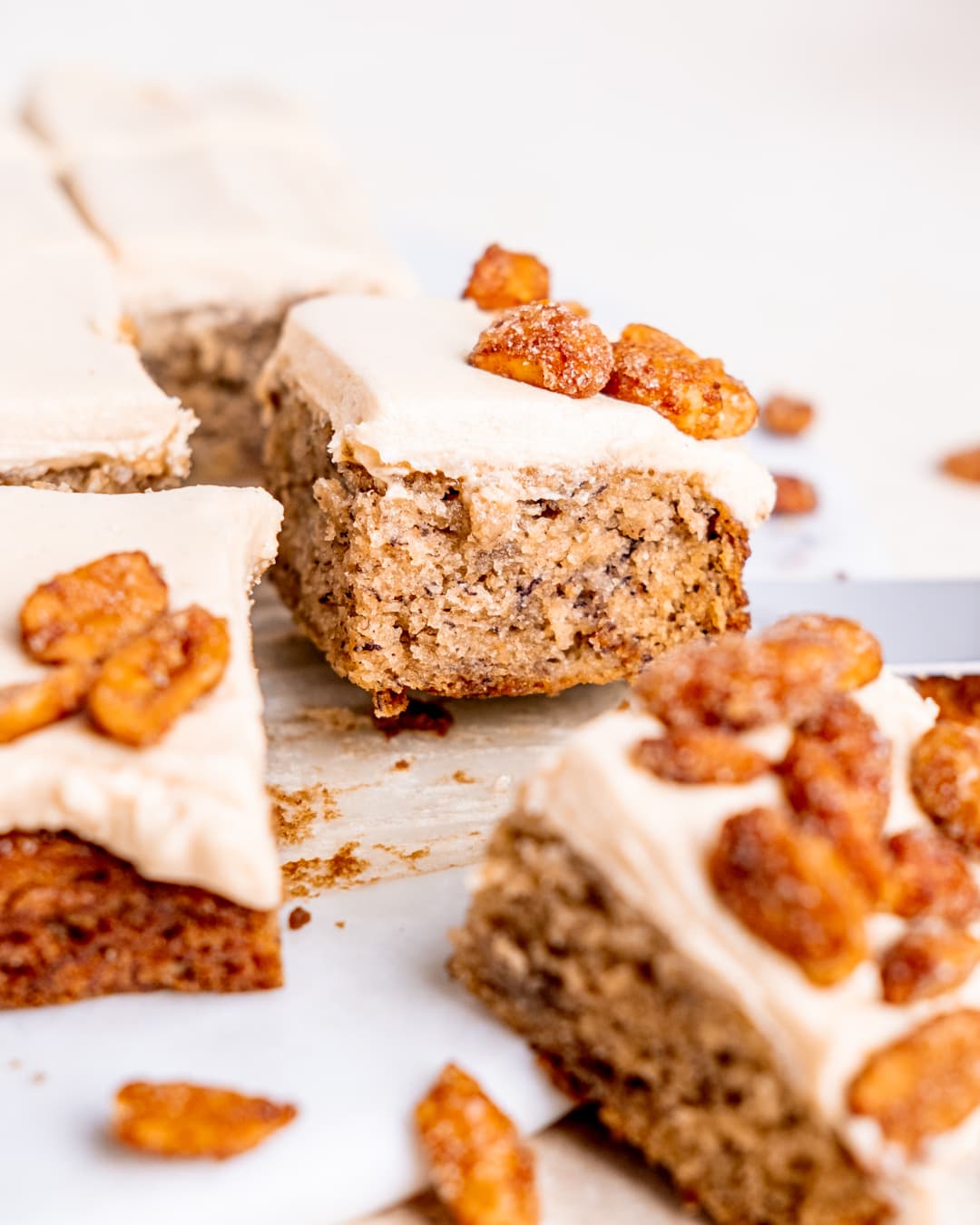 a slice of banana snack cake with frosting and honey glazed peanuts on top