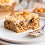 A slice of banana snack cake on a plate with a fork.