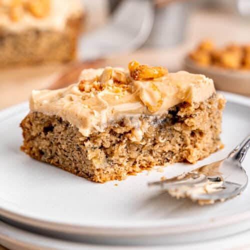A slice of banana snack cake on a plate with a fork.