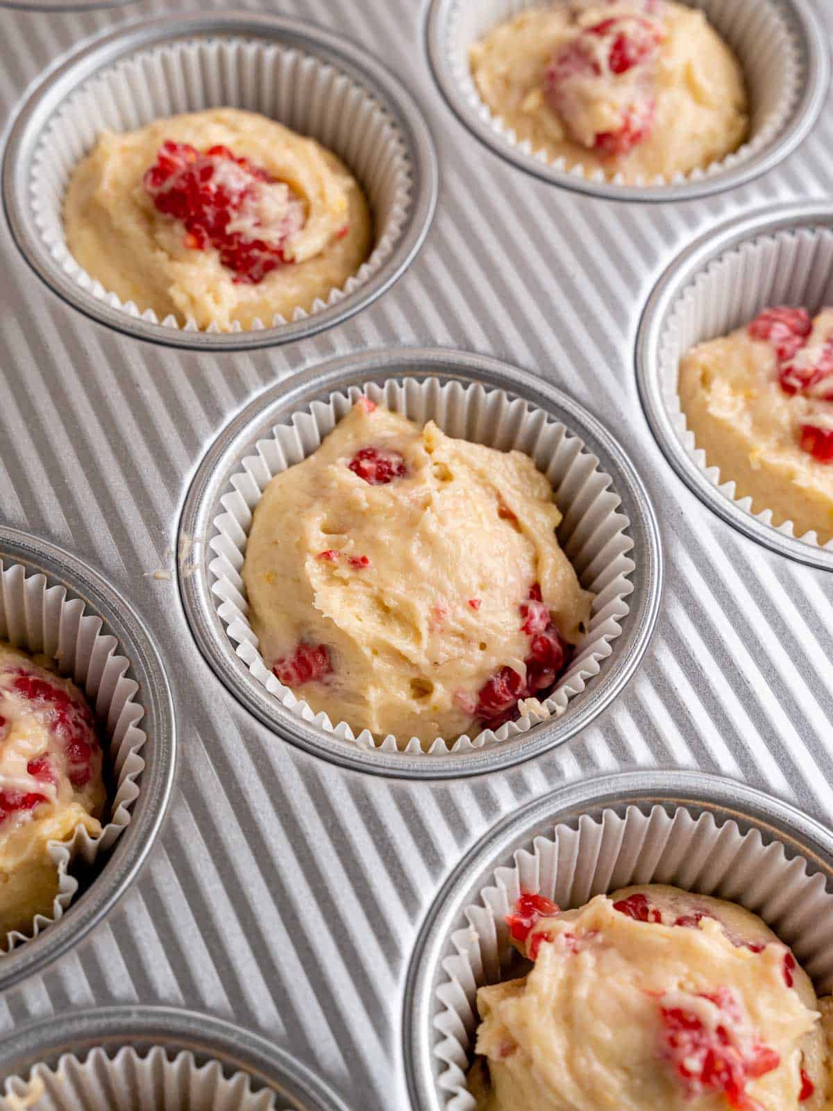 Muffin liners filled with lemon raspberry muffin batter.