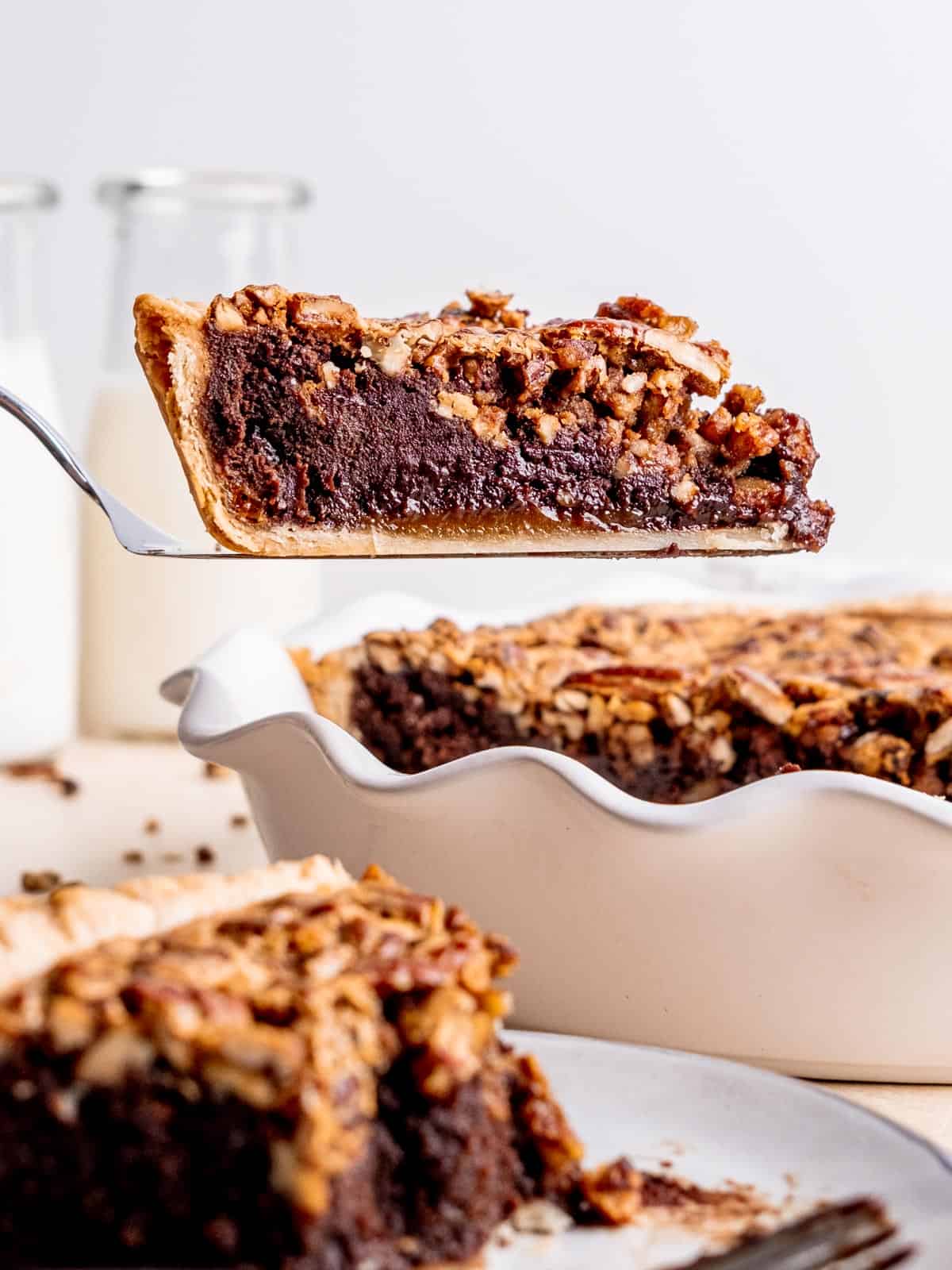 A slice of pecan brownie pie being lifted out of the pie dish.