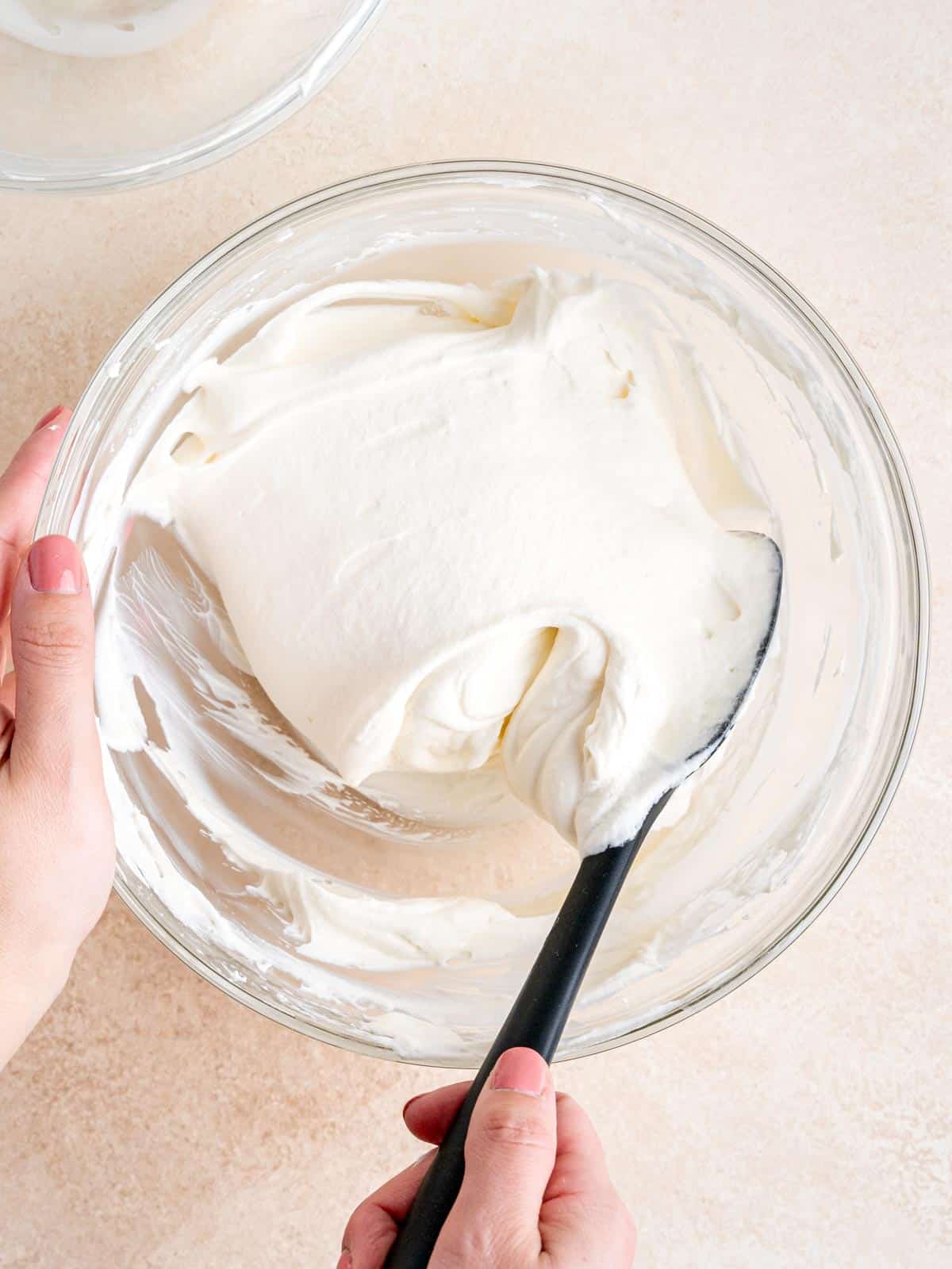 Folding whipped cream into cream cheese mixture with a rubber spatula.