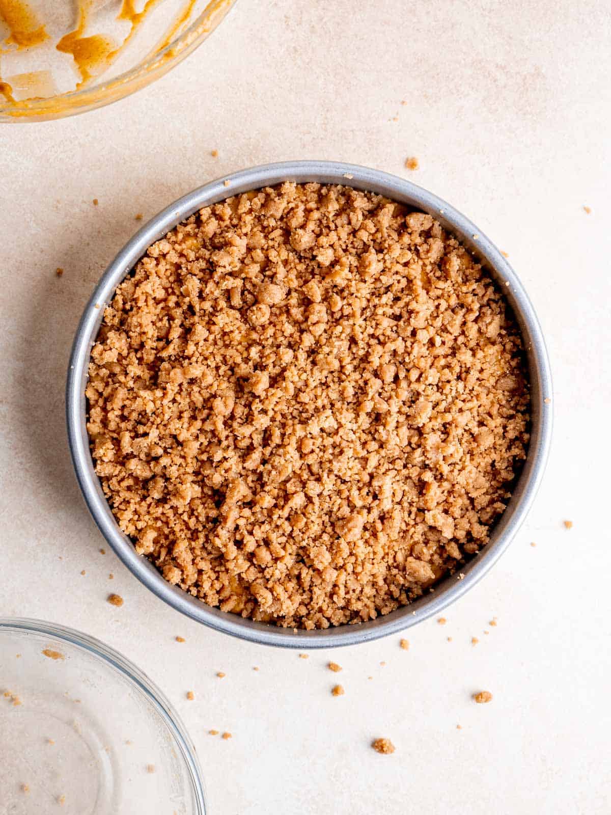 Pumpkin cake batter with cinnamon streusel topping in a round pan.