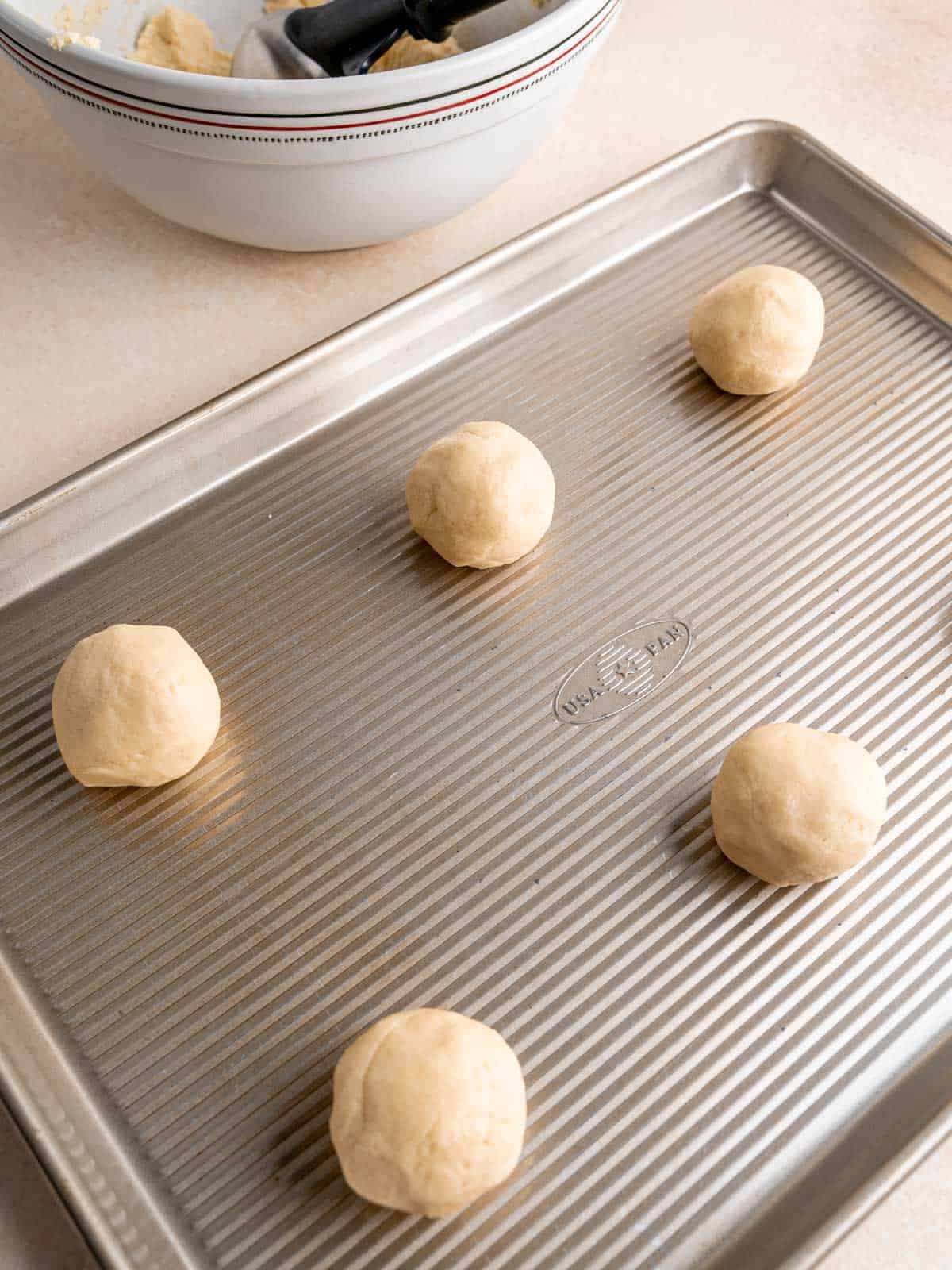 Almond sugar cookie dough balls on a baking sheet.