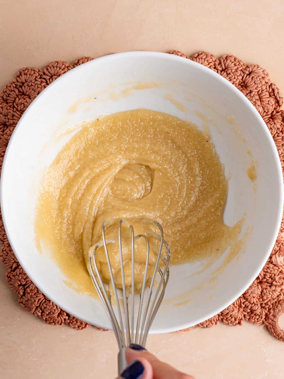 Whisking almond flour and sugar into melted butter and honey.