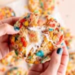 Pulling a Fruity Pebble cookie in half to show the marshmallow filling.