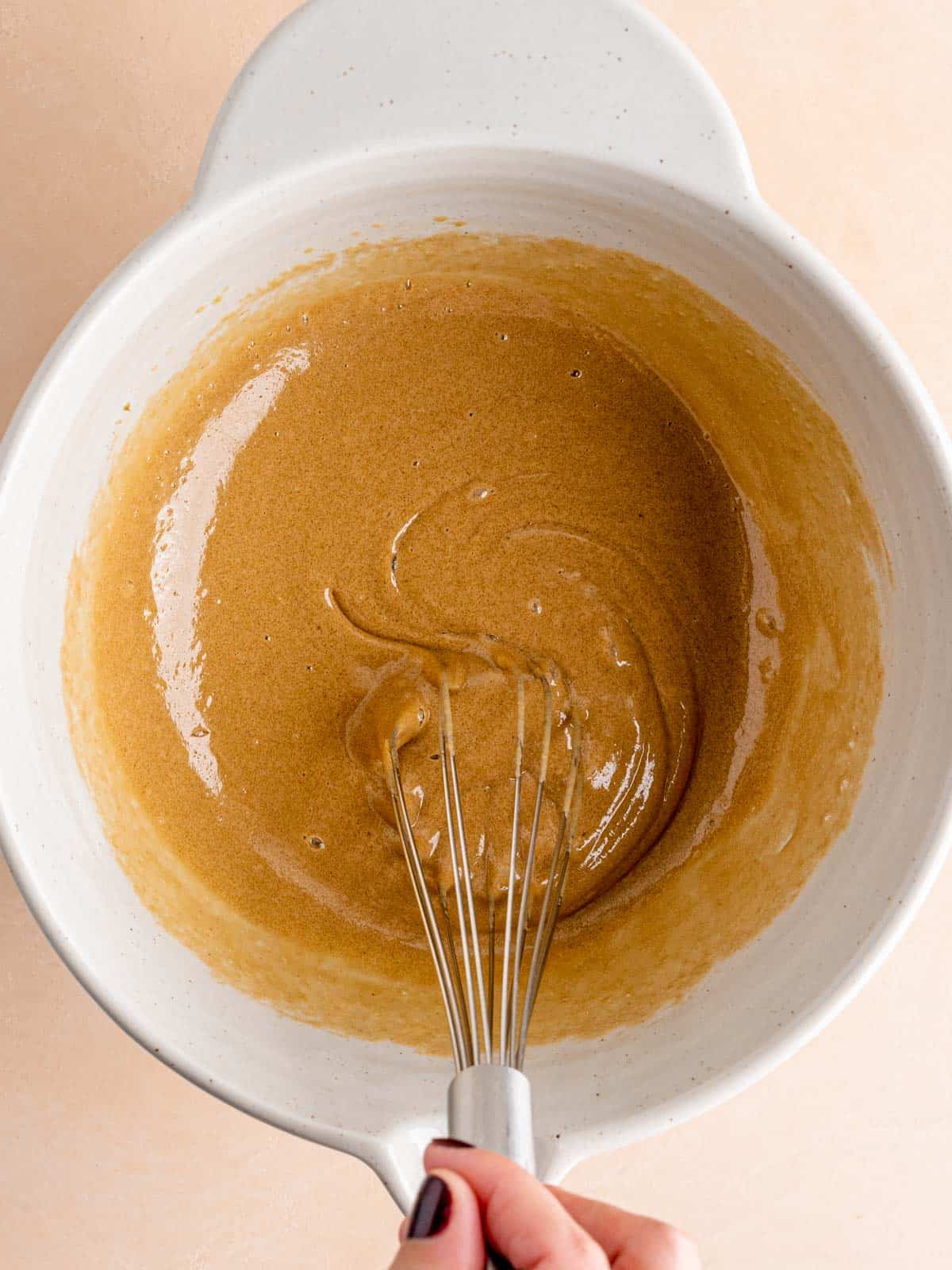 Whisking brown sugar and eggs in a bowl.