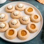 A plate of pumpkin pie filled thumbprint cookies with whipped cream.