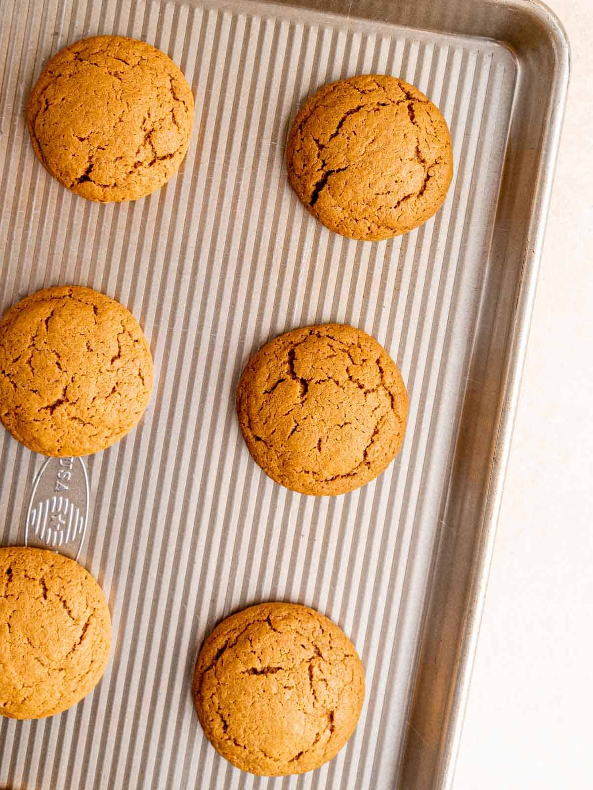 Baked ginger molasses cookies on a baking sheet.