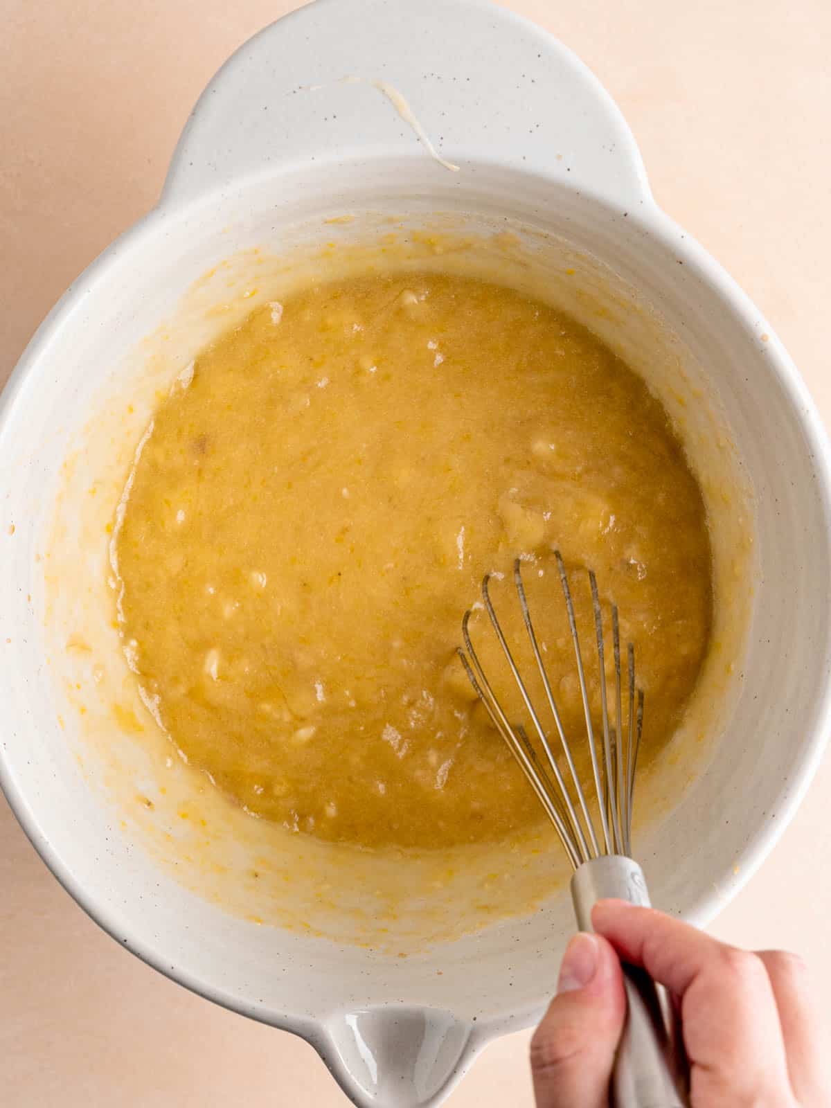 Whisking honey banana bread wet ingredients in a bowl.