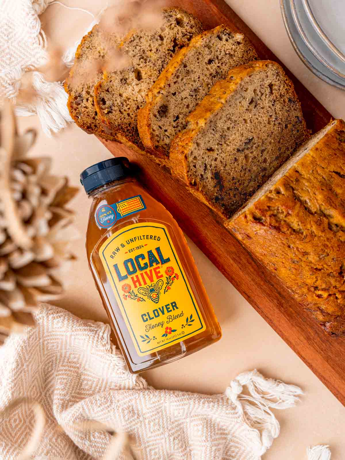 Sliced banana bread next to a bottle of Local Hive Honey.