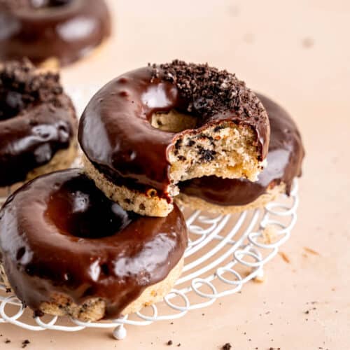 Cookies and cream donuts stacked on a wire cooling rack.