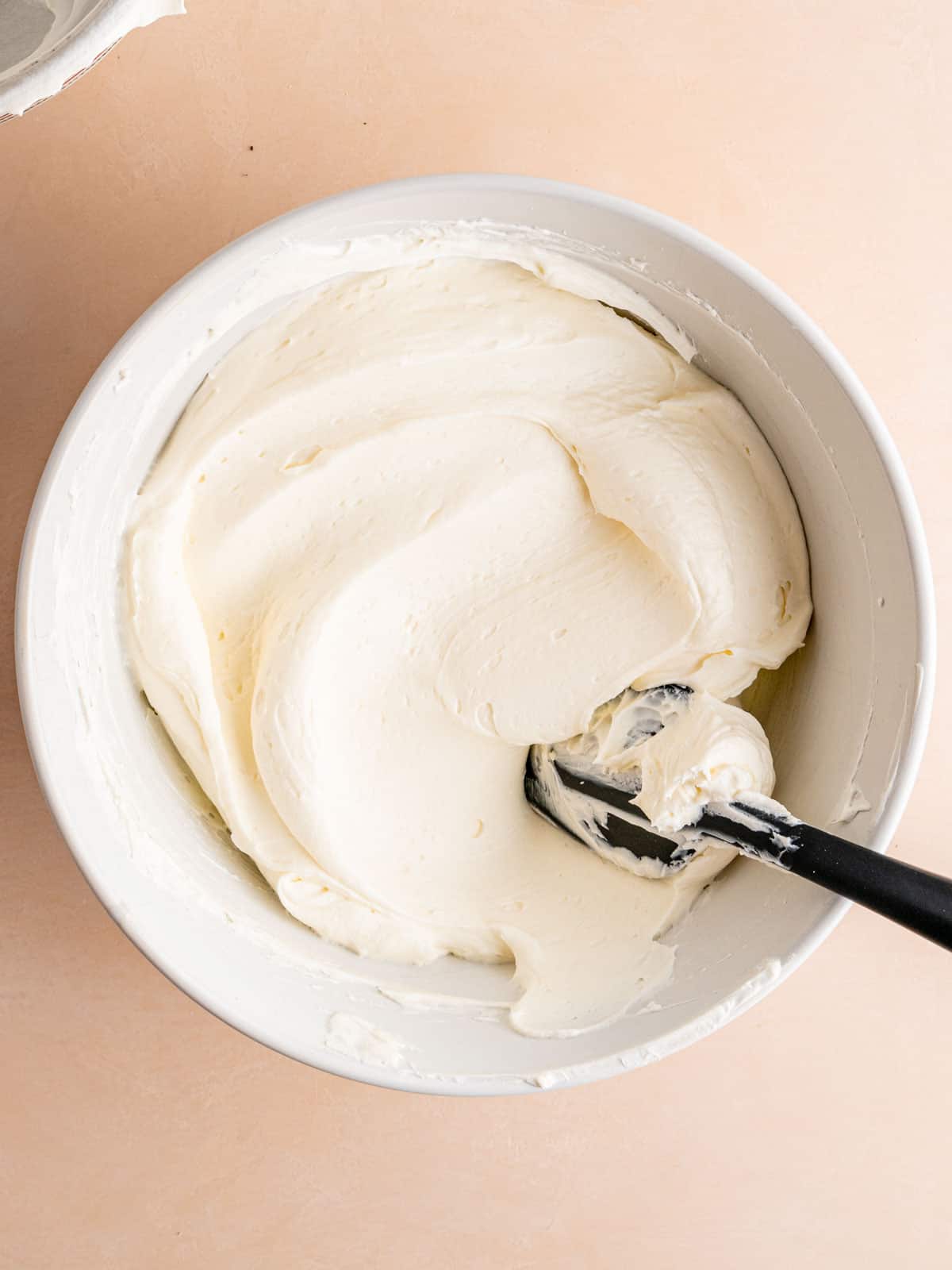 Peppermint cheesecake filling in a bowl with a spatula.