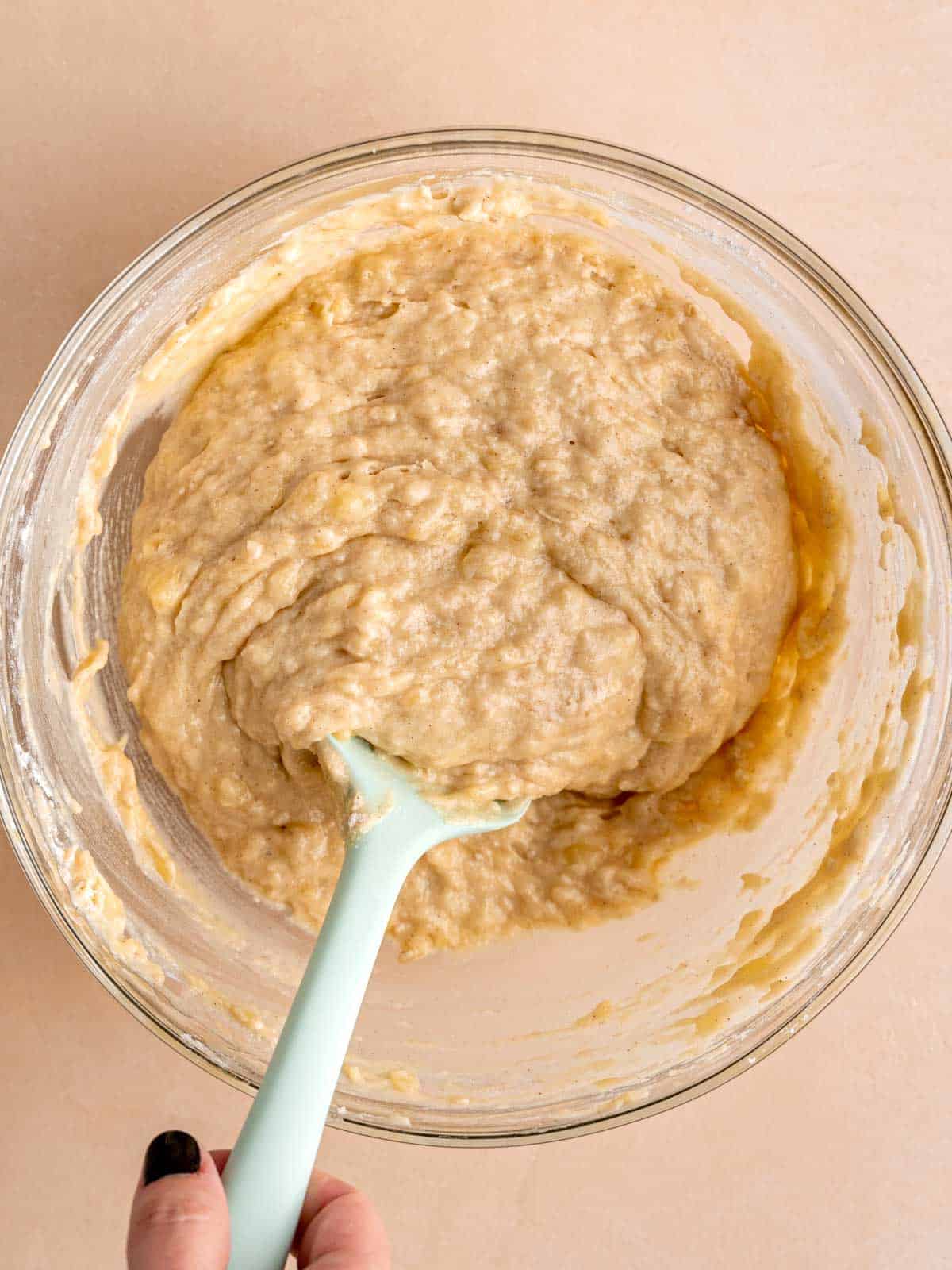 Banana muffin batter in a bowl with a spatula.