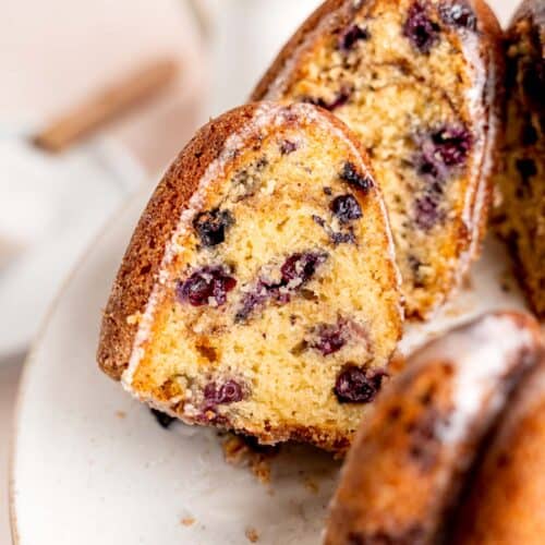 A slice of blueberry sour cream coffee cake sticking out of a bundt cake.