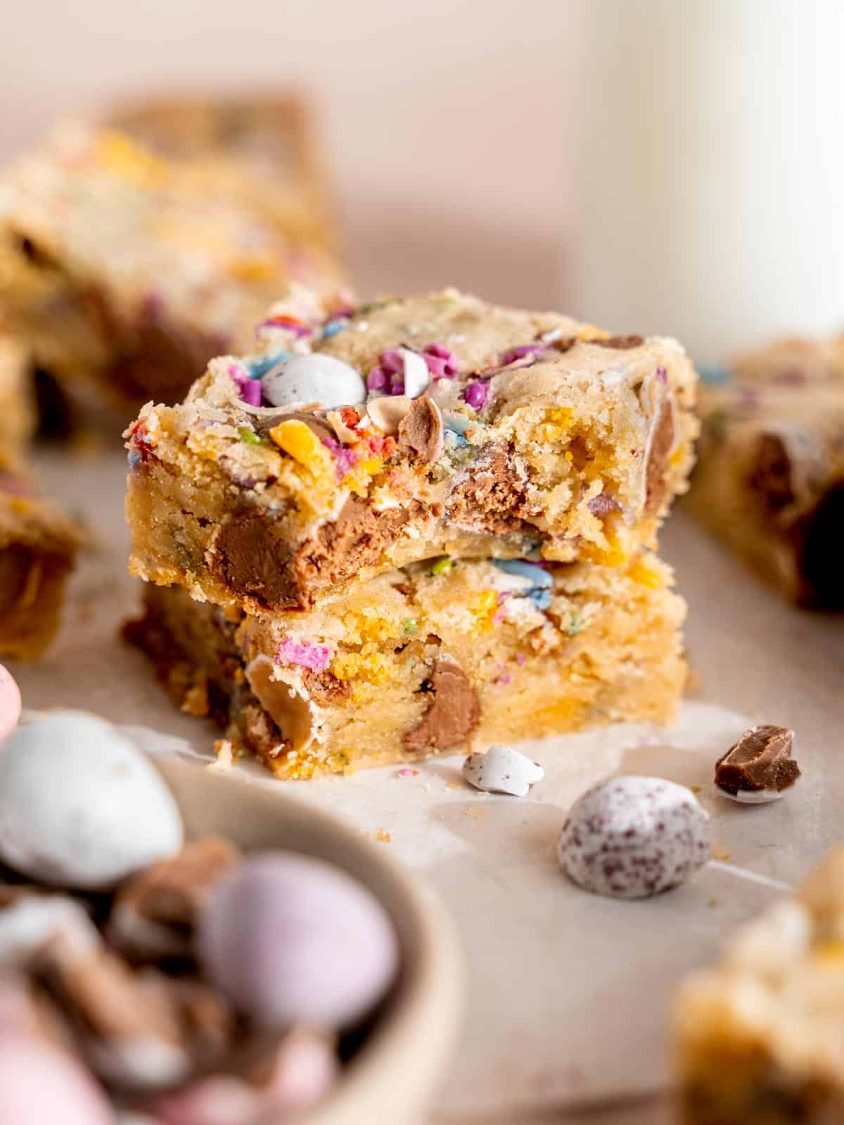 A stack of mini egg Easter blondies with a bite taken out of one.