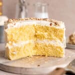 Almond cream cake on a cake stand with slices taken out of it.