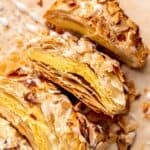 A braided almond danish with icing cut into slices.