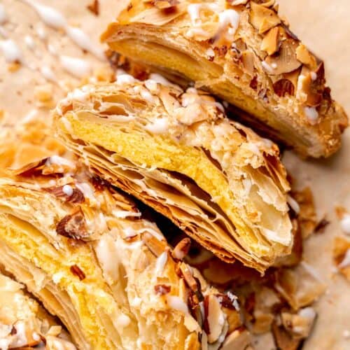 A braided almond danish with icing cut into slices.
