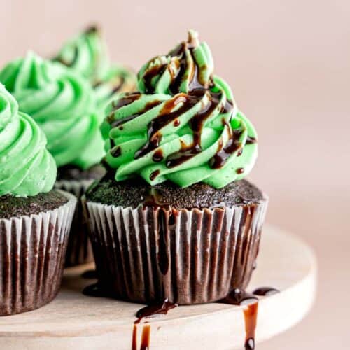 A chocolate mint cupcake with green mint buttercream frosting and a chocolate drizzle.