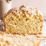A loaf of almond poppy seed cake topped with sliced almonds and almond poppy seed glaze.