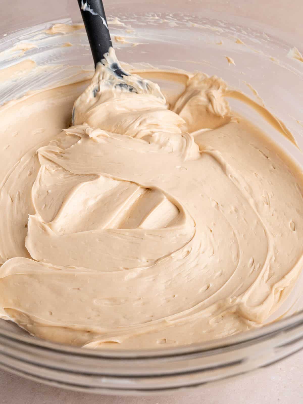 A cookie butter cream cheese mixture in a bowl with a spatula.