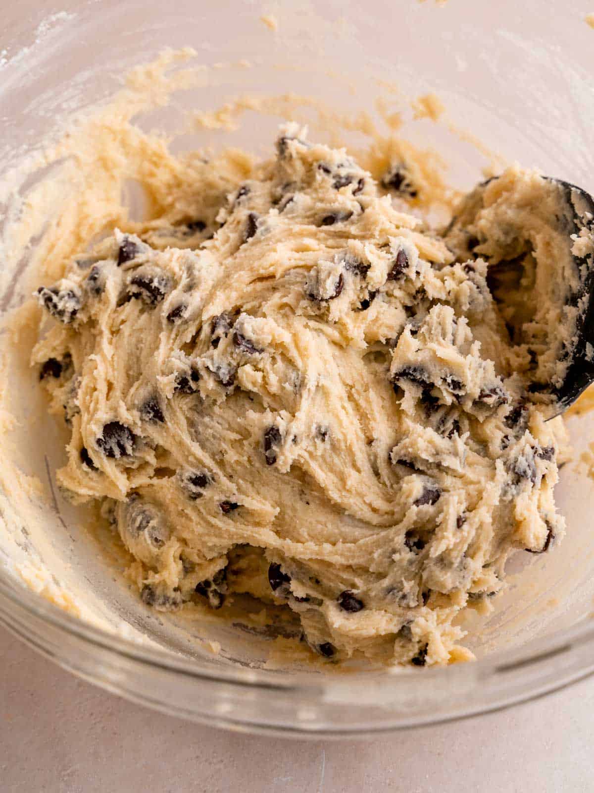 Chocolate chip cookie dough in a bowl with a spatula.