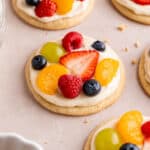 Mini fruit pizza sugar cookies with cream cheese icing and fresh fruit.