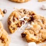 A s'mores cookie cut in half showing the melted chocolate and gooey marshmallows inside.