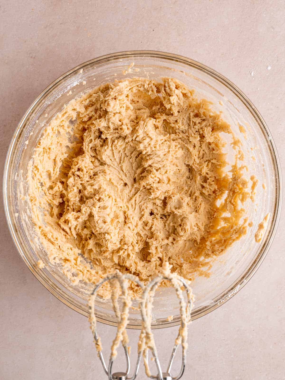 Cookie dough mixed together in a bowl using a hand mixer.