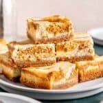 A stack of pumpkin cheesecake bars on a plate.