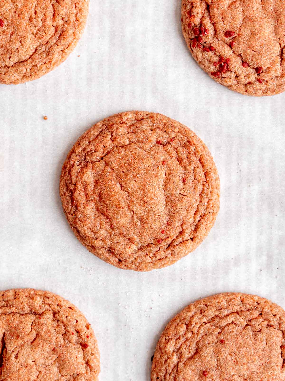 Baked strawberry sugar cookies on a pan with parchment paper.