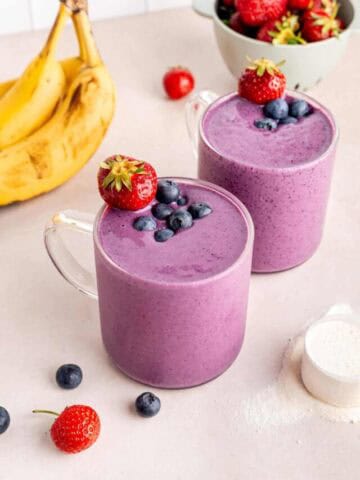 Two banana berry protein smoothies in clear glass cups.
