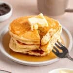 A stack of fluffy kefir pancakes topped with butter and maple syrup.