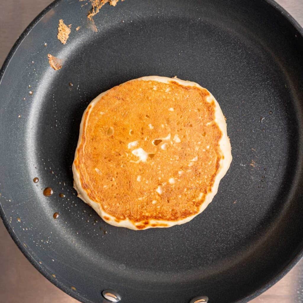 A kefir pancake on a skillet cooked to golden brown.