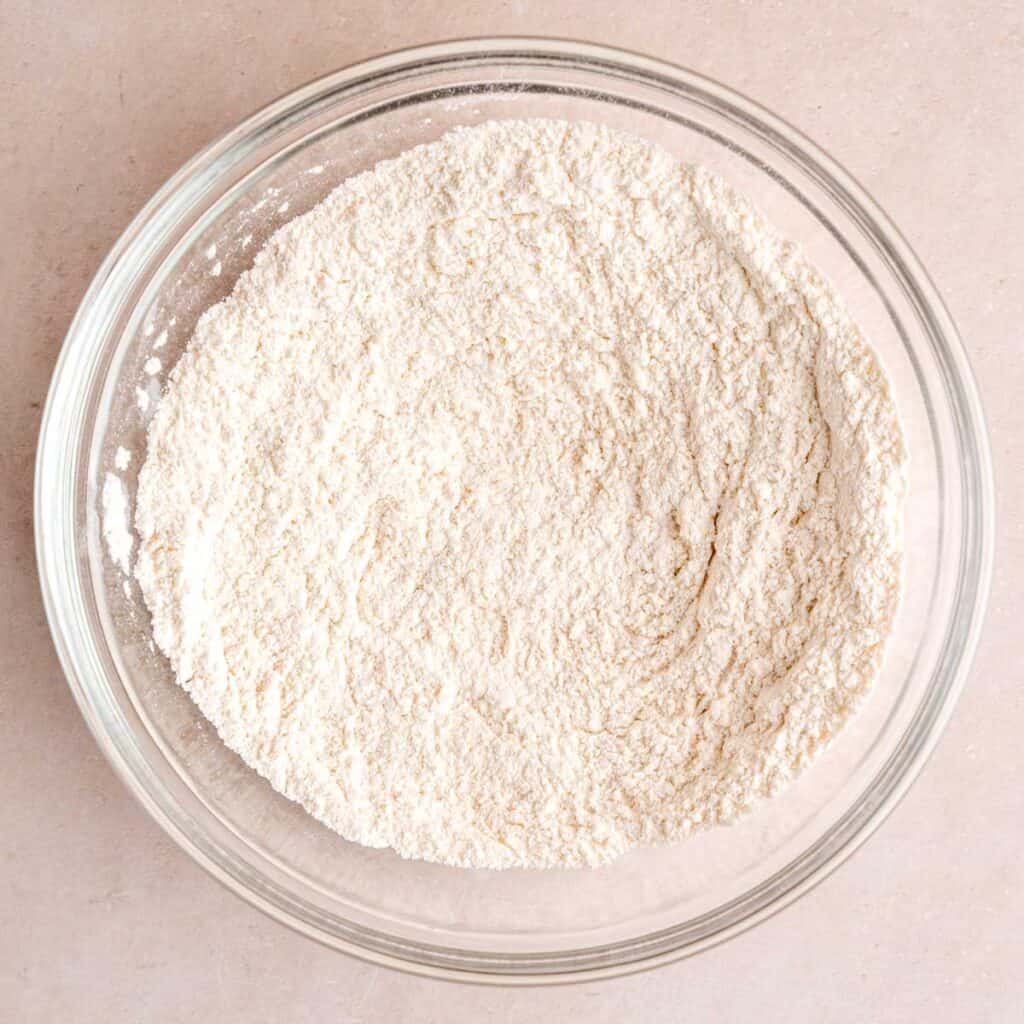 Flour, baking soda, baking powder, and salt mixed together in a bowl.