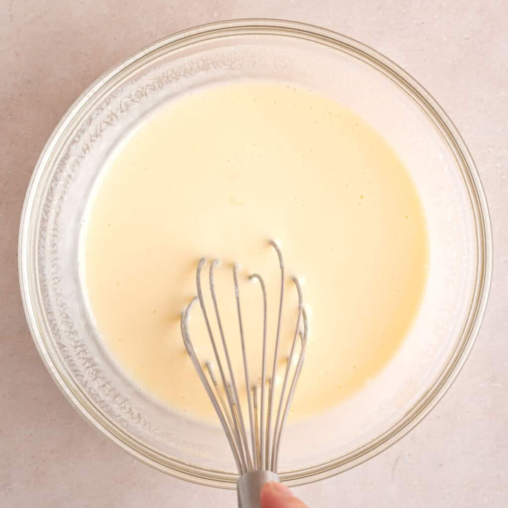Whisking an egg, kefir, and maple syrup in a bowl.