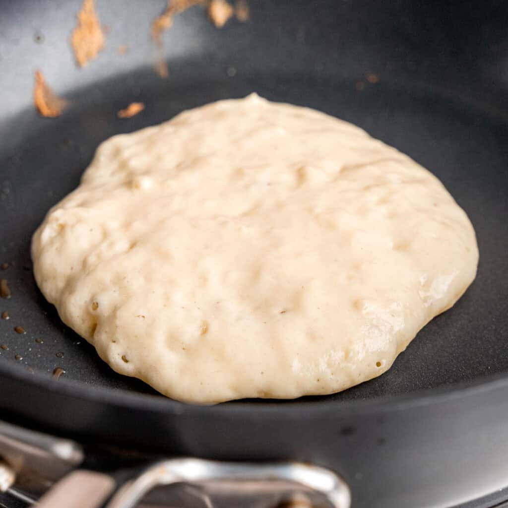 Pancake batter cooking on a hot skillet.