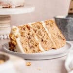 A slice of spiced walnut cake with cream cheese frosting on a plate.
