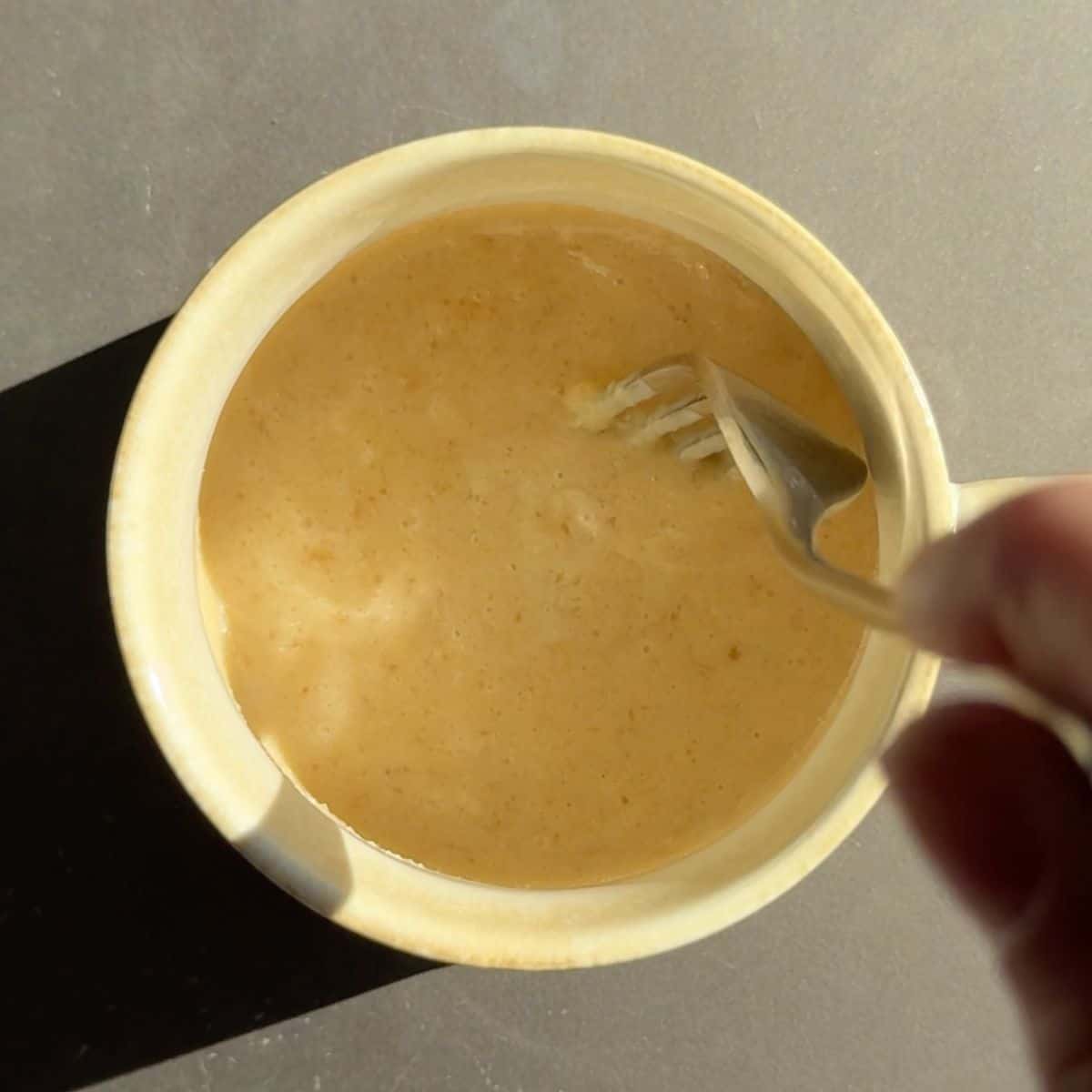 Melted butter, brown sugar, vanilla extract, and kefir in a mug.