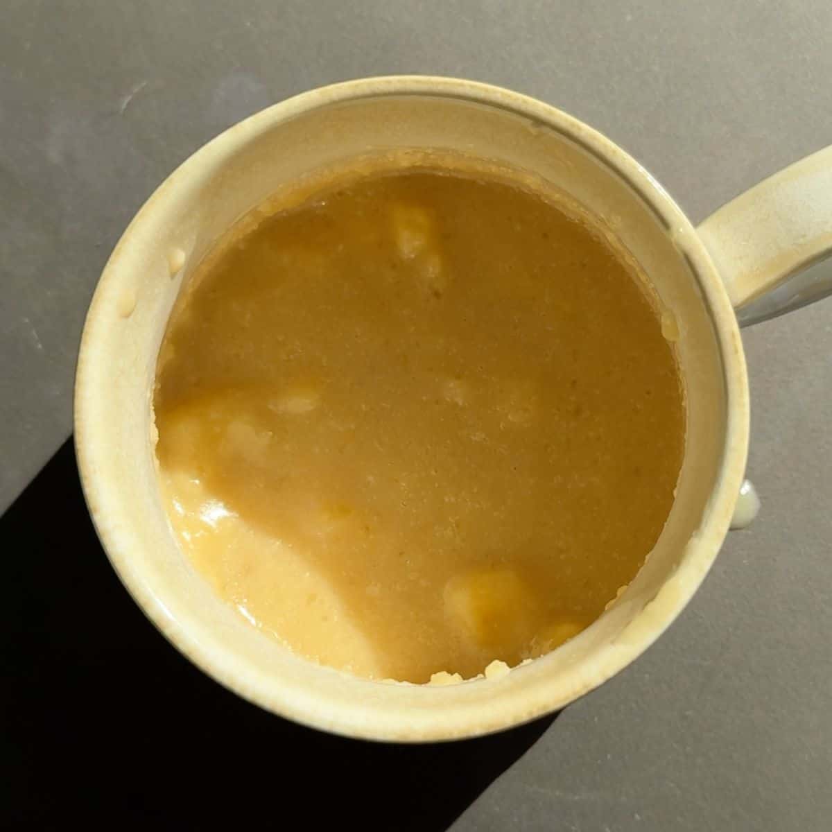 Butter, brown sugar, vanilla, kefir, and banana in a mug.