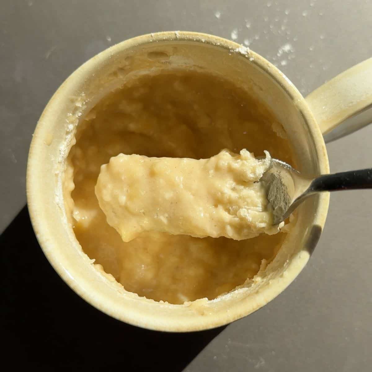 Banana bread batter in a coffee mug mixed with a fork.