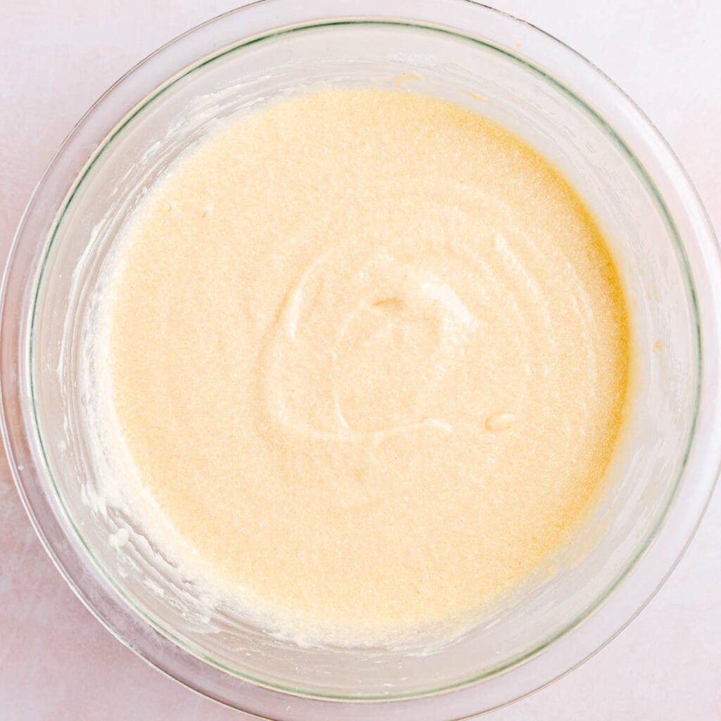 Butter, sugar, eggs, vanilla extract, sour cream, milk, and sourdough discard mixed together in a bowl.