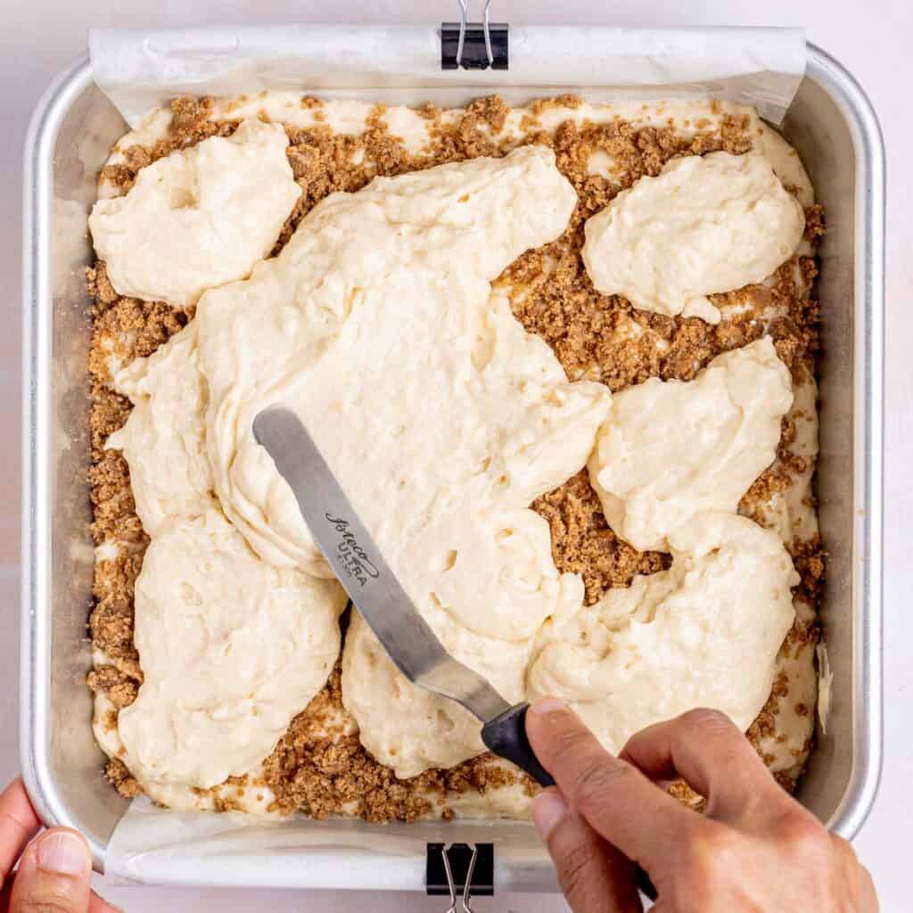 Spreading cake batter over a layer of streusel.